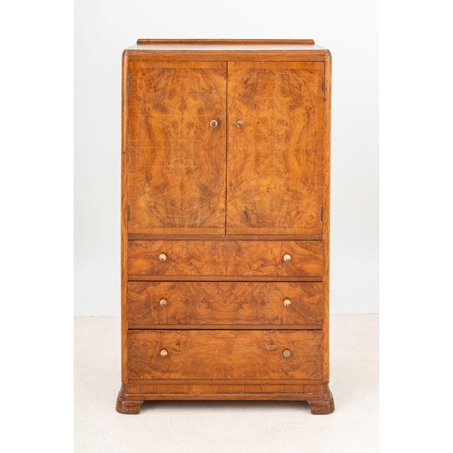 Art Deco Walnut Linen Press, late 1930s, with two doors opening to three shelves above three graduated frieze drawers....