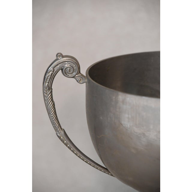 A two-handled silver cup on a turned wooden base engraved with a winners' inscription, carrying the unpolished patina of a...