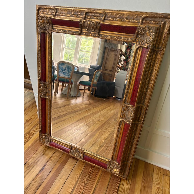 Grand 19th century Gilded Age Style Wall Mirror featuring an ornate & detailed frame with gold gilded moldings & inset red...