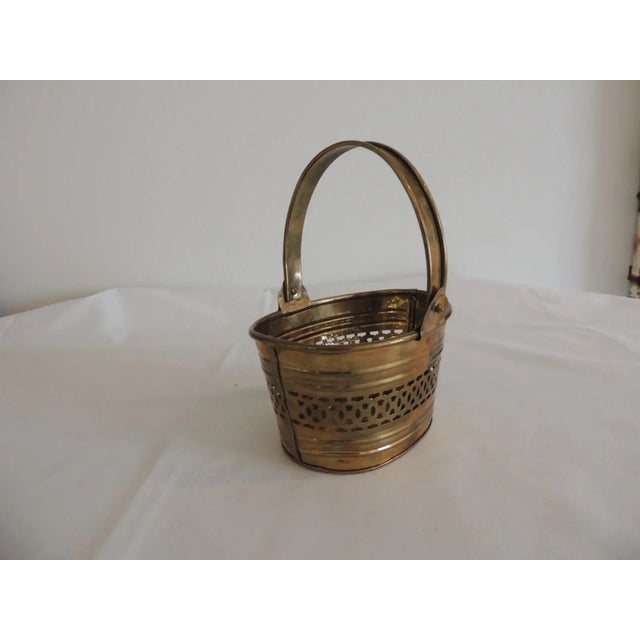 Small Brass Indian Decorative Basket with Handle. Oval shape with pierced body. Size: 5.5"W x 4"D x 7" H to top of handle.