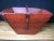 Antique red lacquered wooden rice bucket with metal reinforced corners, tapered square shape and handle across the middle....