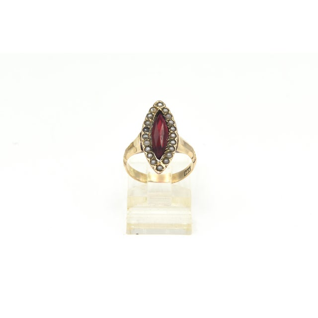 An antique Victorian 14K yellow gold ring featuring an elongated navette-shaped head set with a faceted deep red garnet at...