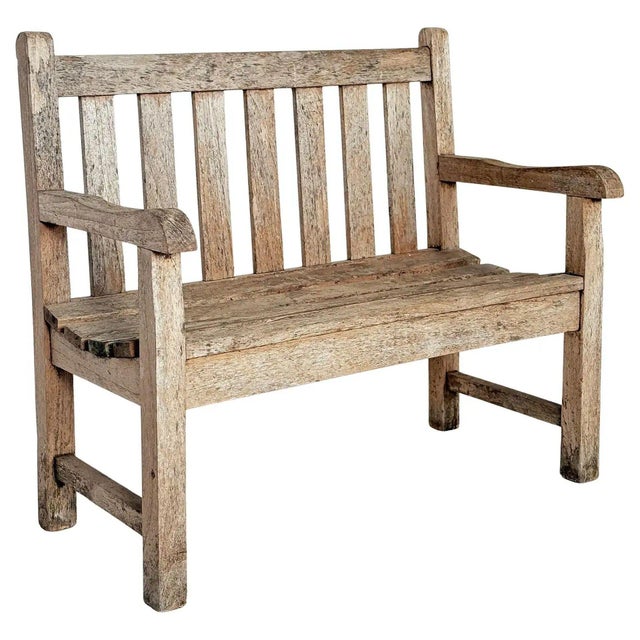 A fine English children's or child's sized garden bench or seat of patinated teak, featuring a slatted back with shaped...