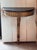 Giltwood wall mount console of demilune form with a black marble top above a frieze carved with vertical fluting, centered...