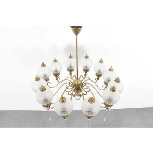 Imposing and sculptural 10-arm chandelier in curved brass with globe diffusers in worked satin glass and brass finishes...