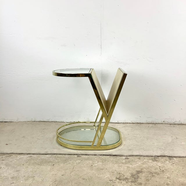 A sculptural vintage magazine rack and side table with the glamorous geometry associated with Hollywood Regency design....