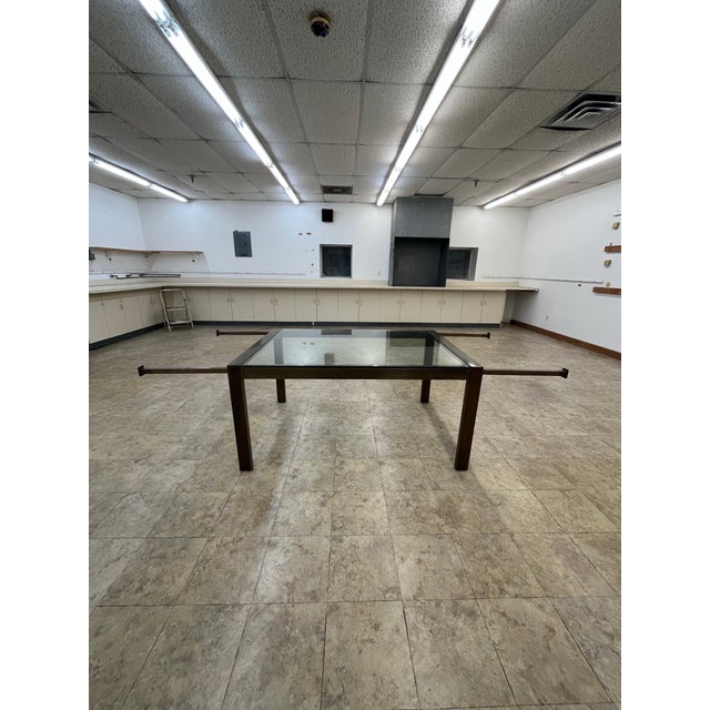 A sophisticated extending dining table by John Stuart, executed in polished brass with a floating glass top. The...
