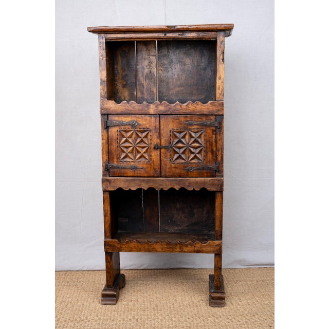 A solid wood bookcase with carved doors and aprons, mid-20th century, Spanish. Features iron T hinges with matching latch...