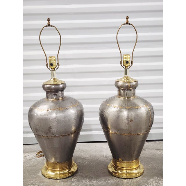 Very unique pair of vintage 1990's handcrafted silver metal table lamps with brass accents. The pair of lamps are...
