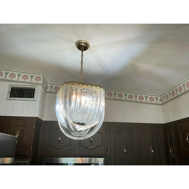 Spectacular vintage chandeliers featuring multiple curved clear lucite ribbons suspended from brass tone frame. These are...
