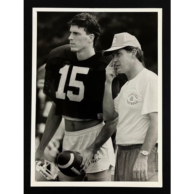 1990 photograph of UNC Tarheels quarterback Todd Burnett and head coach Mack Brown. Publication information on the back....