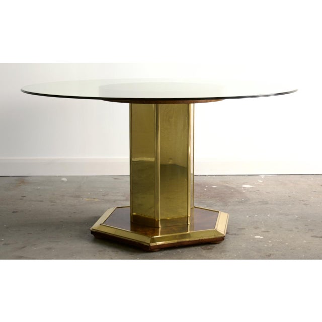 Substantial and beautifully made, this pedestal dining table pairs a faceted hexagonal column clad in polished brass with...