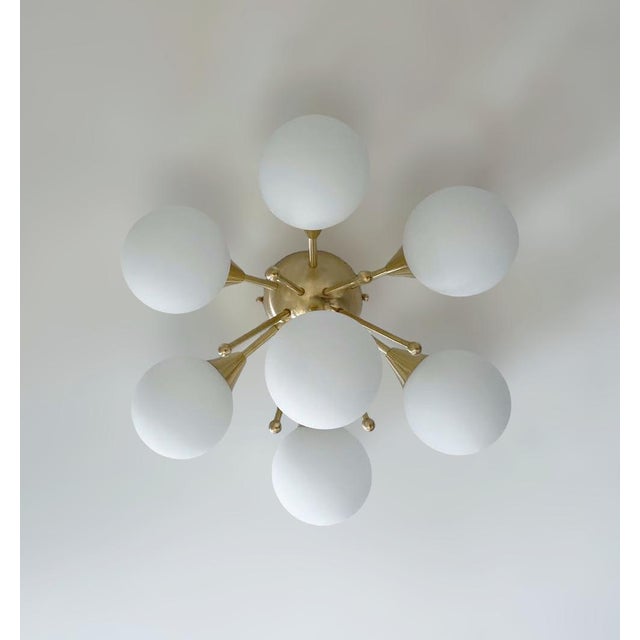 Italian flush mount with seven matte white Murano glass globes mounted on solid brass frame in unlacquered natural brass...