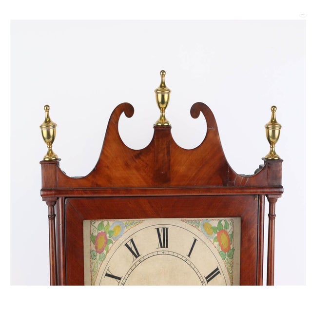 A mahogany pillar-and-scroll shelf clock with a broken-scroll pediment, three brass urn finials, slender turned columns,...