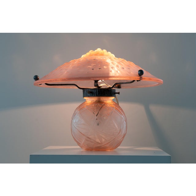 A French Art Deco table lamp by Muller Frères, made around 1930s. The lamp composed of molded pink glass with metal...