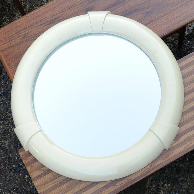 A vintage cream resin wall mirror with three decorative accents. This piece is attributed to the mentioned designer/maker....