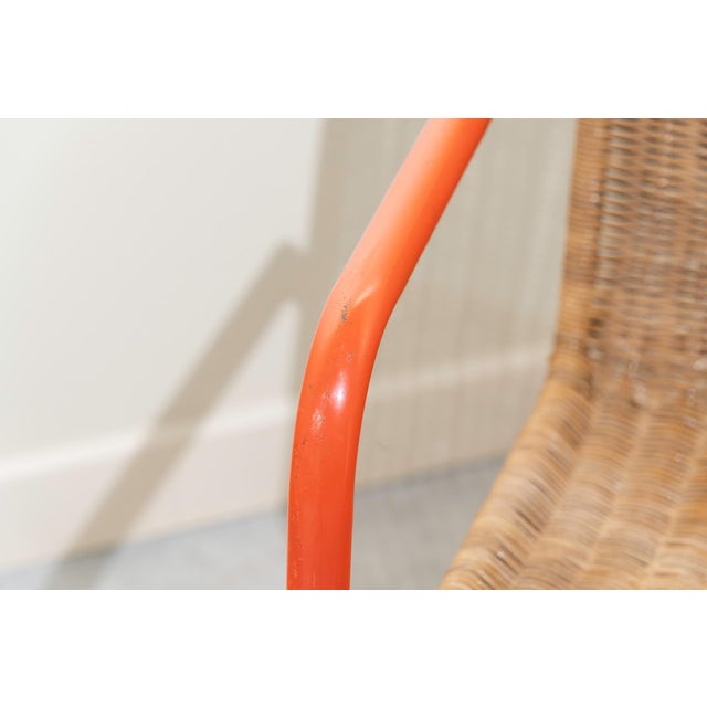 Armchair with orange tubular steel frame with rush seat and backrest.