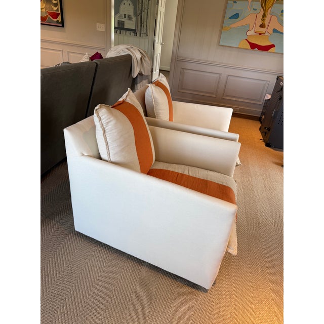 Pair of Lee swivel chairs in a cream twill fabric with a fun orange racing stripe down the center. Chairs are slipcovered...