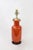 This vintage porcelain vase lamp is glazed in a deep, rustic orange color and mounted on a dark wood base. Single detail...