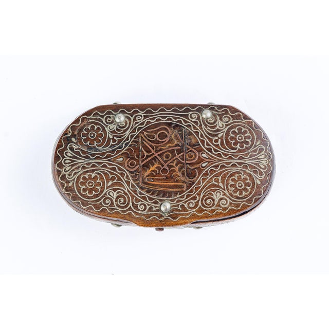 A finely crafted antique oval trinket box, the wood body inlaid throughout with silver wire in a scrolling floral pattern,...
