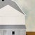 Frontier by Justin Wheatley is an acrylic painting on canvas of a white barn and its attached shed standing on a wide band...