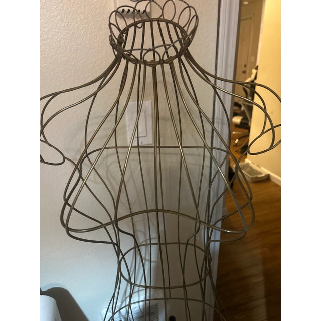 A decorative and functional antique wire dress form, perfect for displaying garments or as a unique sculptural piece.