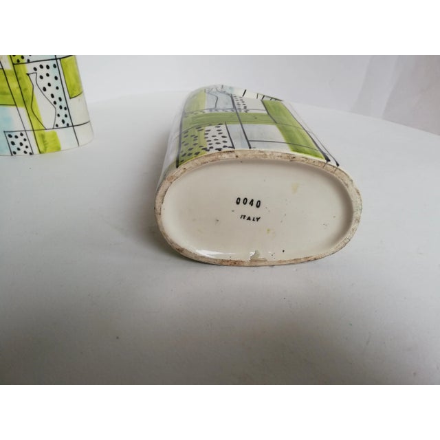 This ceramic bottle shaped vase is decorated with abstract drawings and fish in yellow and black colors. It was produced...