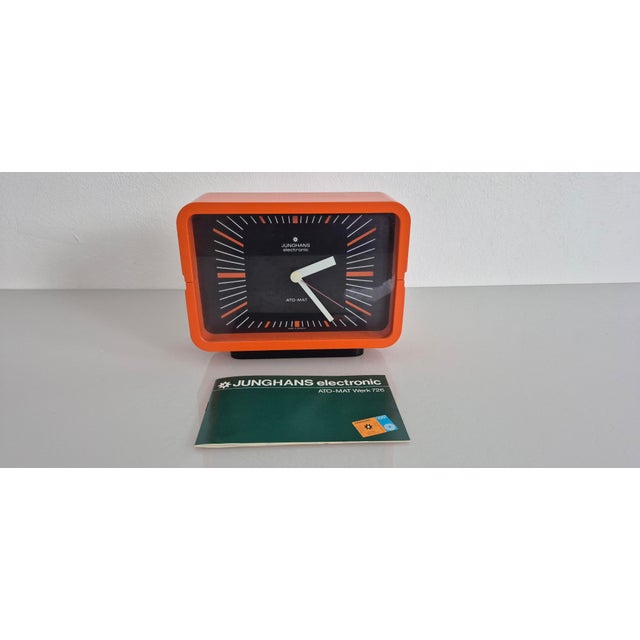 Orange Junghans table clock in its original packaging, including the instruction manual. Designed as the official...