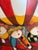 A charming and whimsical oil on canvas painting in the distinctive Roybal style, featuring three playful children riding...