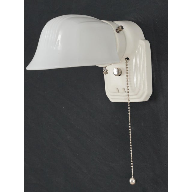 Art Deco style white porcelain wall sconce with a pull chain and glass shade. This sconce requires one Edison style medium...