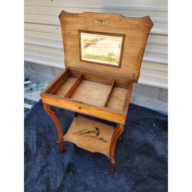 A charming early 20th century marquetry inlaid vanity or sewing table featuring intricate floral designs on both the top...