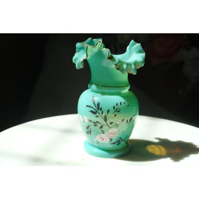 Beautiful teal Fenton Art glass bud vase with a ruffle edge with a painted gold rim. Hand painted with floral motifs on...