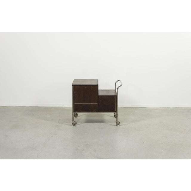 Beautiful Art Deco serving trolley from 1930s, executed in varnished wood with steel frame. Key is included. Condition...