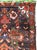 This mid-20th-century Turkish Anatolian rug presents an exuberant floral composition set against a deep charcoal-brown...
