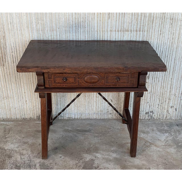 About A Spanish walnut side table with single drawer, scalloped apron, carved legs and iron side stretcher from the late...