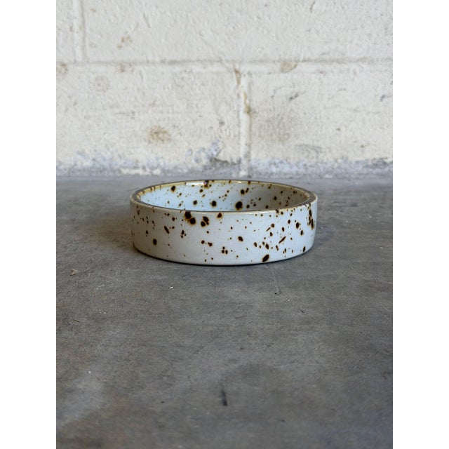 This vintage ceramic bowl features a clean cylindrical silhouette decorated with a rustic, hand-applied aesthetic. The...