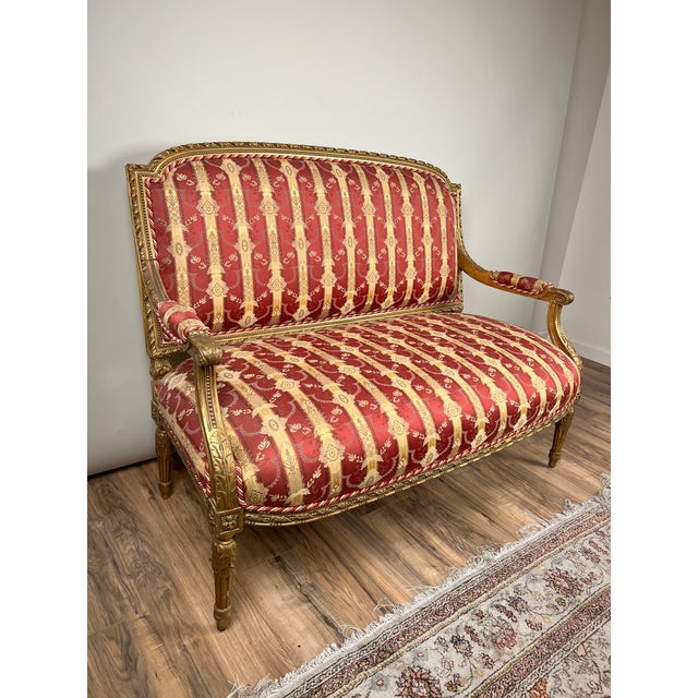 This elegant late 19th century Louis XVI style giltwood settee captures the refined symmetry and neoclassical restraint...