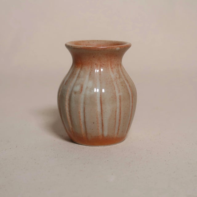 This handcrafted studio pottery bud vase features a softly rounded, bulbous form with a gently flared rim, showcasing...