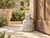 A weighty stone piece with the silhouette of an old bell: a broad, flared foot rising through carved horizontal bands at...