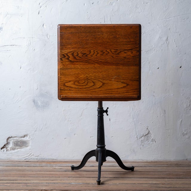 A Keuffel & Esser cast iron and oak drafting or drawing table, 1920s. 26 inches wide by 20 inches deep by 48 inches tall...