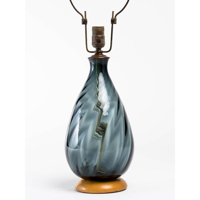 Blenko smoke blue glass lamp with circular wood base. Original hardware and finial. Overall height measures 27 inches,...