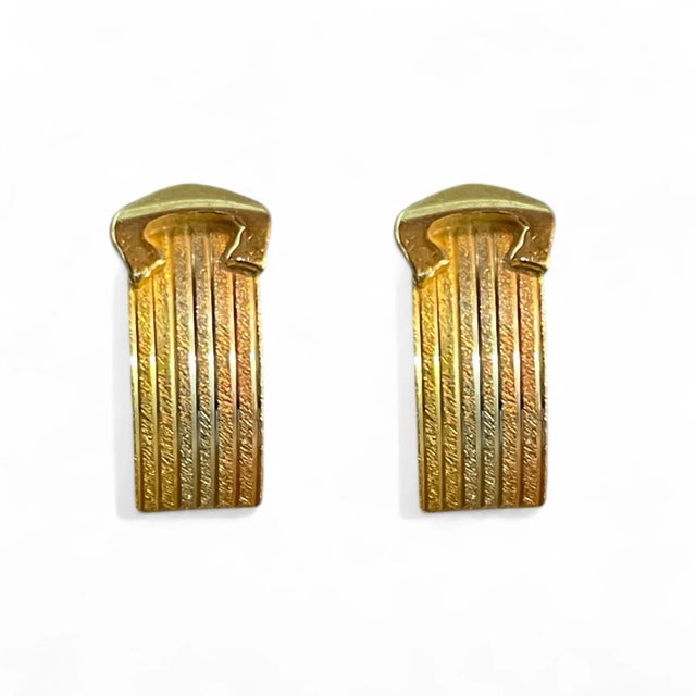 These stunning 18K yellow gold earrings feature a ribbed texture with curved details that exude a sleek and timeless...