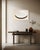 A pale, veiled oval sits low against a deep charcoal field, the white and grey layered thin enough in places that the...