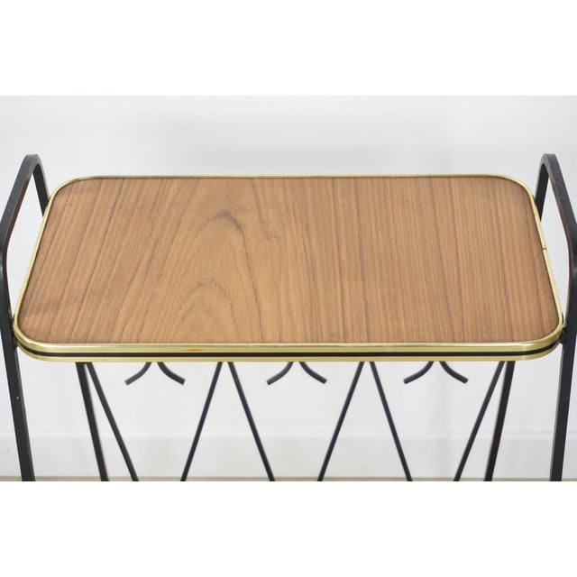 1950s design side table or end table with a wrought iron structure forming a magazine rack and wooden shelf.