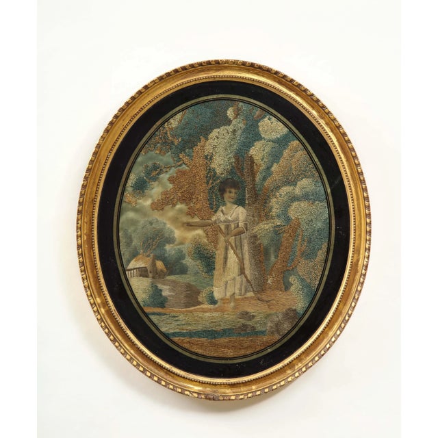 Extremely fine embroidery of a neoclassical maiden dressed as a shepherdess in a forest with a rustic thatched cottage in...