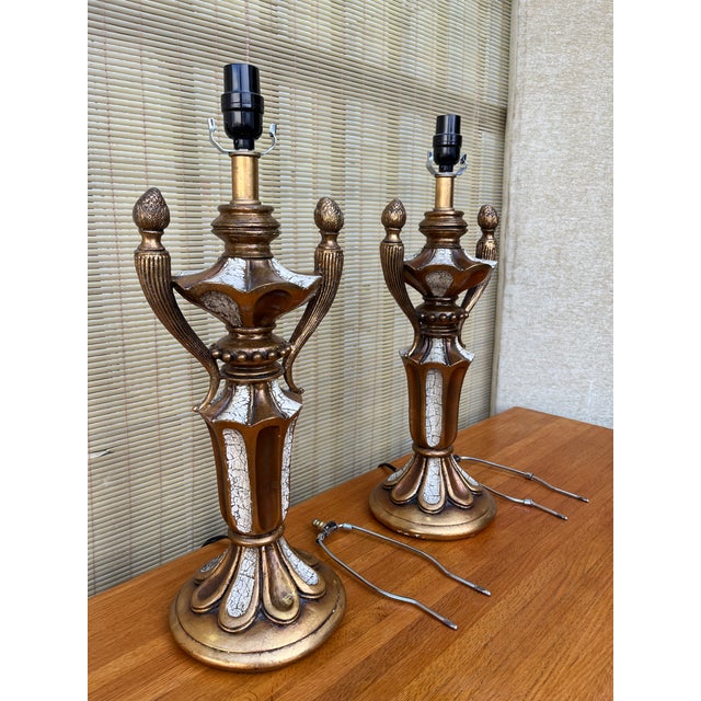 A Pair Of Mid Century Hollywood Regency Neoclassical Revival Style Trophy Table Lamps. Circa 1960s Features a faux-aged...