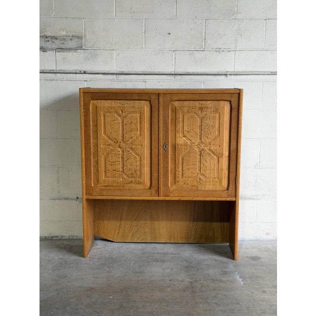 This striking wooden shelving unit features a distinctive upper block with twin doors displaying beautifully carved...