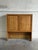 This striking wooden shelving unit features a distinctive upper block with twin doors displaying beautifully carved...