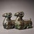 This is a matching pair of cast bronze vessels in the form of recumbent rams, featuring extensive gold and silver inlay...