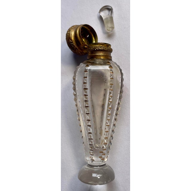 This is a beautiful, early perfume bottle with a crystal stopper and a repousse-patterned brass hinged cap and collar...